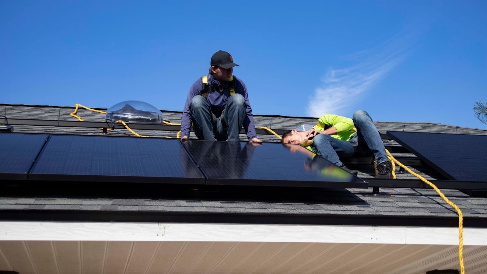 Two workers installing a solar panel on a roof