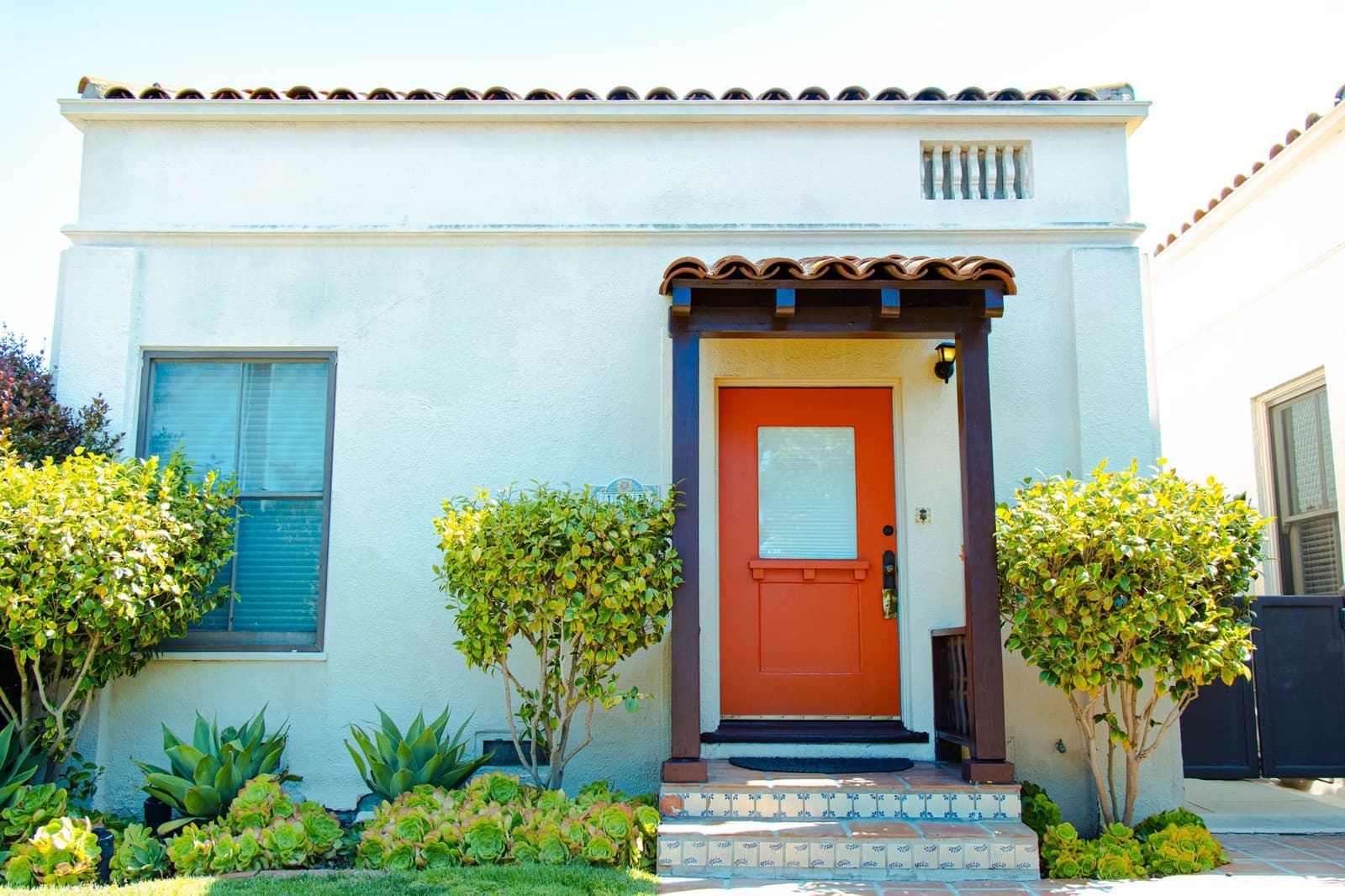 Stucco house with tile awning and orange door