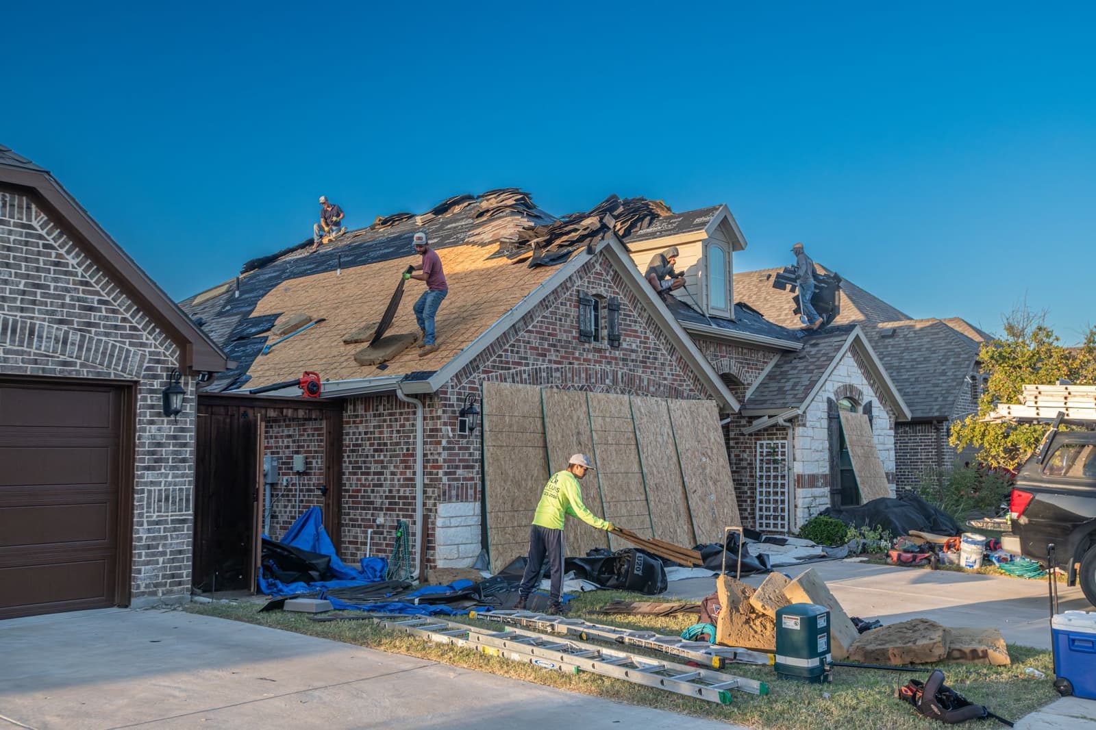 Roofers stripping the roof of a brick house