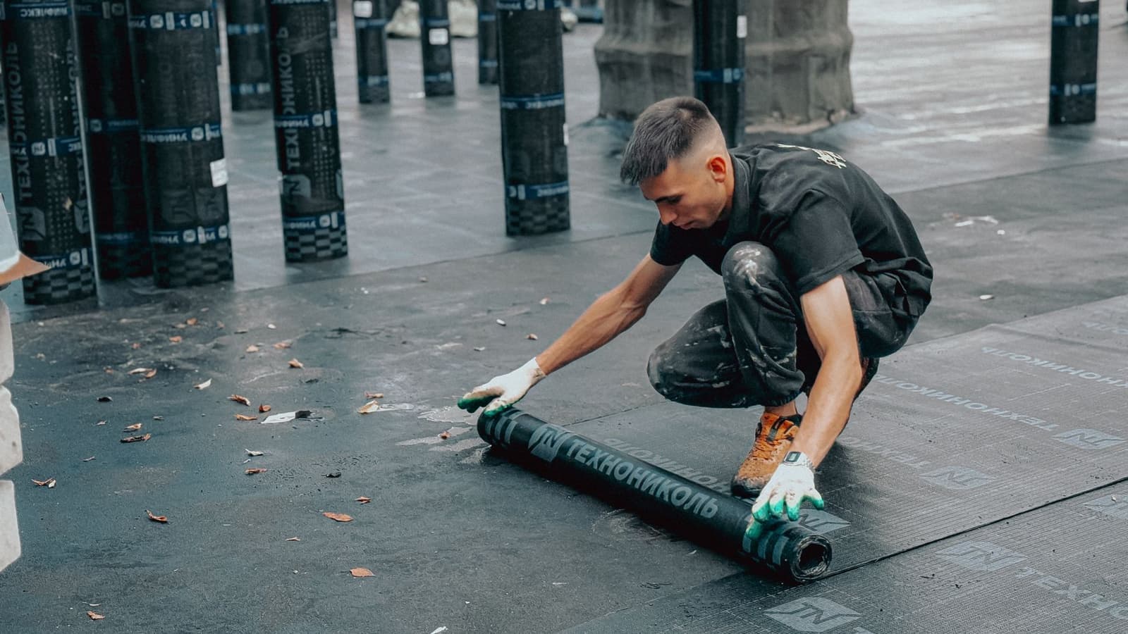Roofer unrolling membrane on a flat roof