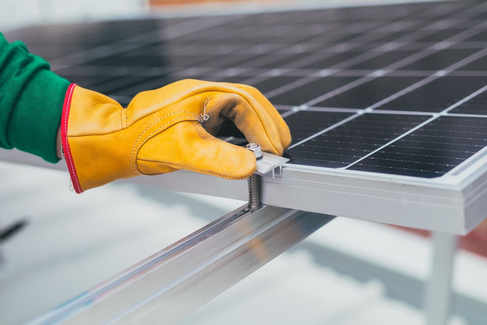 Gloved hands securing a solar panel frame on a roof