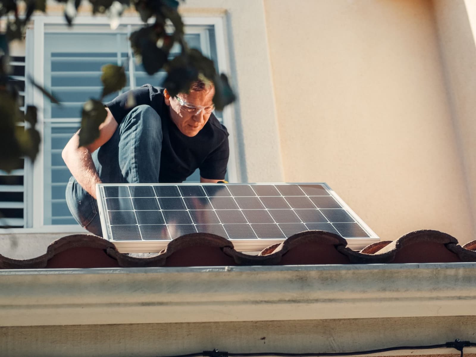 Installer lifting a solar panel onto a tile roof