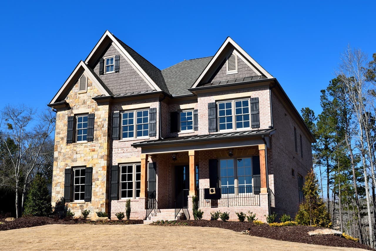 Stone front house with shingle roof under blue sky