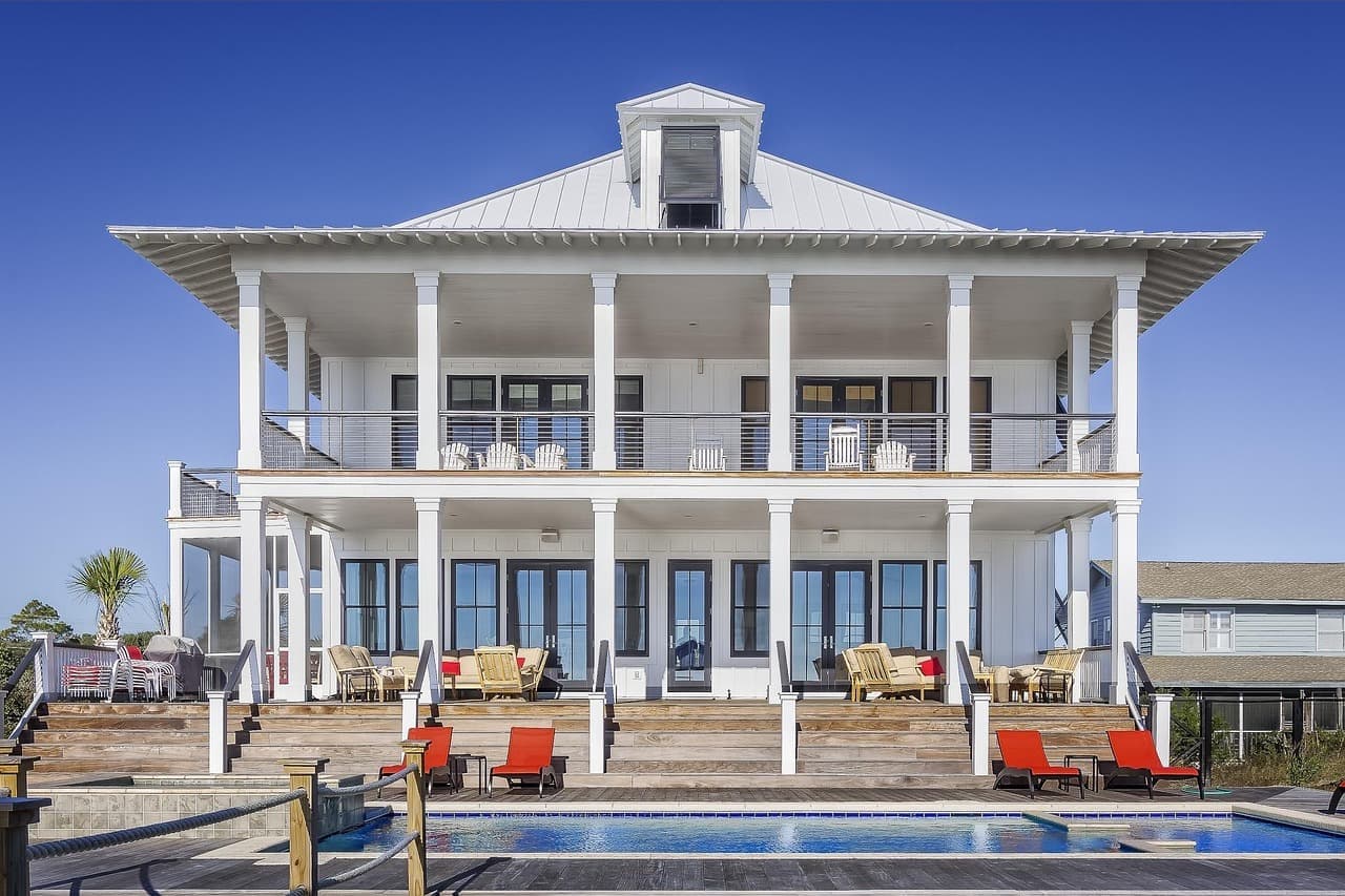 White two-story house with light metal roof and pool
